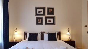 A neatly made bed with white linens and two towels, a wooden headboard, and two bedside lamps. - The Heritage - located in in the center of Glenelg (Glenelg)