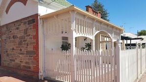 A house with a white picket fence, a brick wall, and a covered porch. - The Heritage - located in in the center of Glenelg (Glenelg)