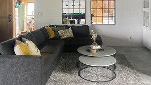 A modern living room with a sectional sofa, a round coffee table, and arched windows.
