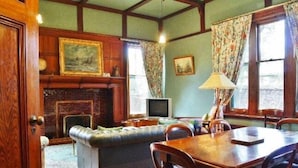 A cozy room with a fireplace, a sofa, a dining table, and a television.