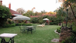 A well-maintained backyard with a lawn, a table with chairs, and a stone wall.