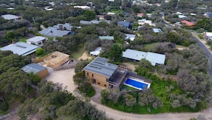 Vue aérienne d’un quartier résidentiel avec des maisons, une piscine et un chantier de construction.