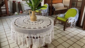 A cozy living area with a round table, a wicker chair, and a sofa. - Cozy and charming house with pool and gardens in a beachfront condominium! (Camaçari)