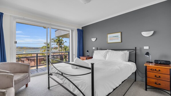 A modern hotel room with a balcony, a bed, a desk with a chair, and a view of the sea. - Quays 6 - Amazing Central Location With Views! (Merimbula)