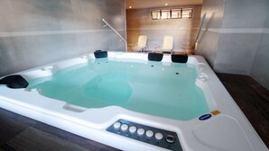A hot tub with control panel, two lounge chairs, and a small table.