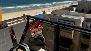 A balcony with a view of the beach and ocean.