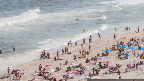 A crowded beach with people sunbathing and swimming.