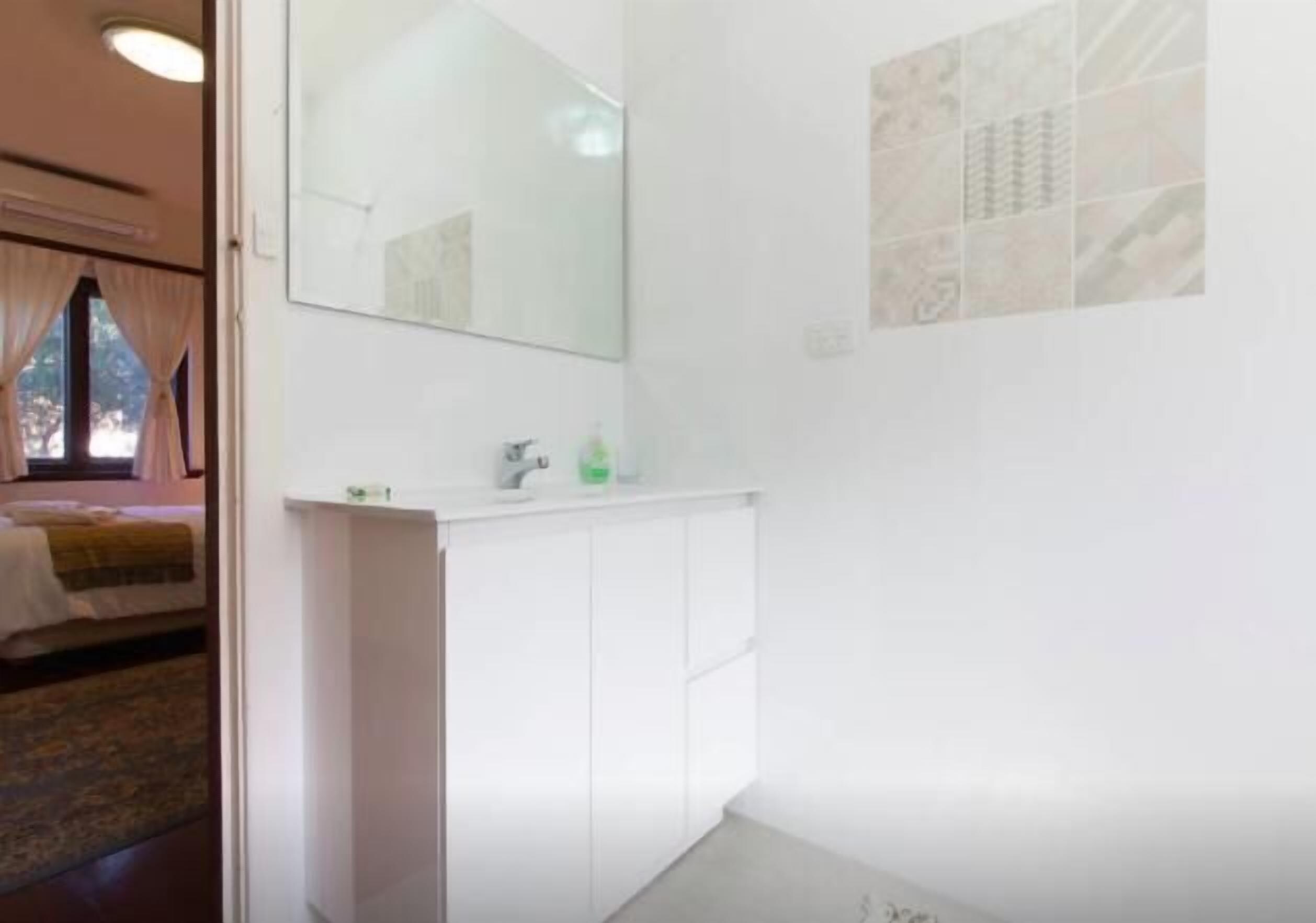 A bathroom with a white vanity, a mirror, and a shower area.