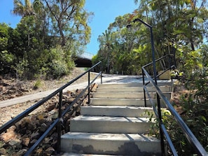 A concrete staircase with metal railings, surrounded by trees and vegetation. - Arbour Rest Expansive Ocean Views (Agnes Water)