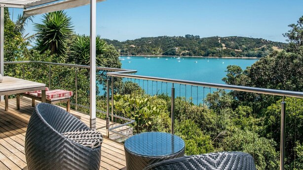 A deck with outdoor furniture overlooking a bay with boats.