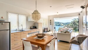 A modern kitchen with a dining area, a large window, and a balcony with a view.