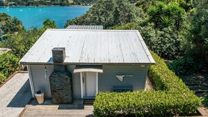 A house with a metal roof, stone chimney, and a view of a lake.