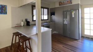 Een moderne keuken met een centraal eiland, roestvrijstalen apparatuur en een raam dat voor natuurlijk licht zorgt.