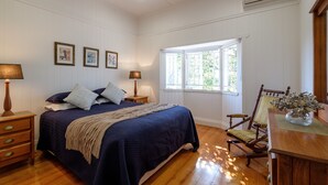 A bedroom with a large bed, wooden floor, white walls, and a window with natural light. - Fantastic base for business meetings, dinner parties or family get together! (Toowong)