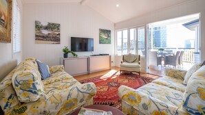 A living room with patterned sofas, a flat-screen TV, and a large window with a view of buildings. - Fantastic base for business meetings, dinner parties or family get together! (Toowong)
