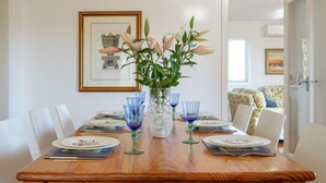 A dining table set with plates, glasses, and a vase of flowers. - Fantastic base for business meetings, dinner parties or family get together! (Toowong)
