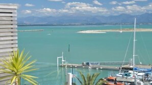 A marina with boats docked, a clear sky, and mountains in the background.