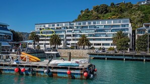 A waterfront property with a dock, boats, and a modern building with balconies.