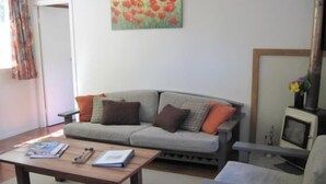A living room with a grey sofa, a wooden coffee table, and a television. - Te Mata Lodge - 2 Bedroom Cottage (Te Mata)