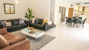 Ein modernes Wohnzimmer mit einer Sofagarnitur, einem Couchtisch und einem Essbereich mit einem Glastisch und Stühlen.