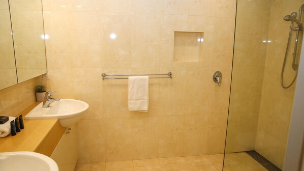 A bathroom with a sink, mirror, towel rack, and shower.