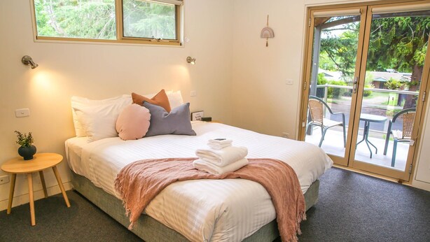 Ein Schlafzimmer mit Bett, Nachttisch und Blick ins Freie durch eine Schiebetür.
