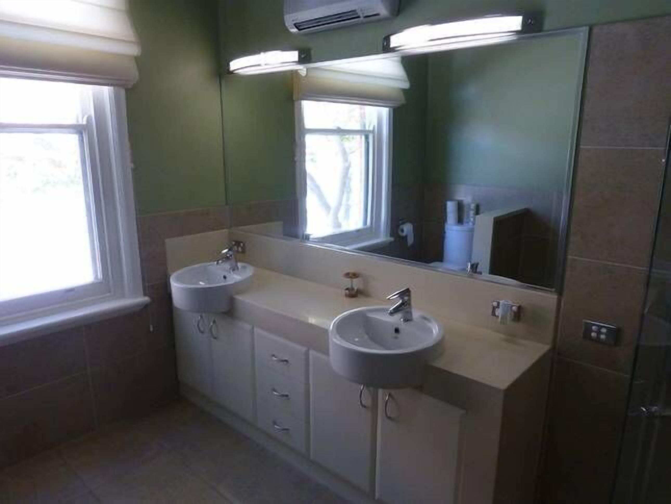 A bathroom with two sinks, a mirror, and a window.