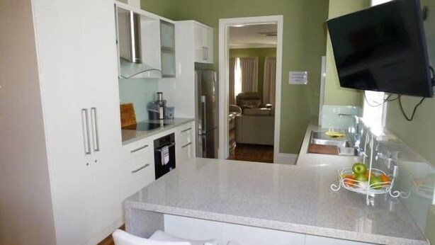 A modern kitchen with white cabinets, a granite countertop, and a built-in TV.