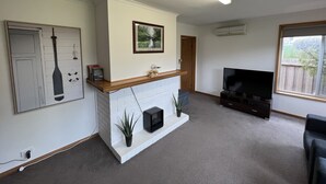 Ein Wohnzimmer mit Kamin, Fernseher und einem großen Fenster.