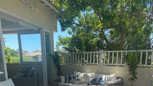 An outdoor patio with wicker furniture, a round table, and a white fence. - Wonderful house in Geribá, 4 suites, balcony and gourmet area. (BÚZIOS)