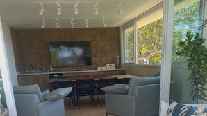 A modern living space with a kitchen area, a dining table, and two sofas. - Wonderful house in Geribá, 4 suites, balcony and gourmet area. (BÚZIOS)