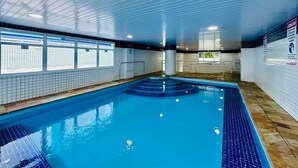 An indoor swimming pool with tiled walls and a blue pool floor. - Ubatuba coverage for families - up to 12 people (including babies and children) (Ubatuba)