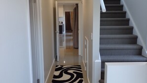 A modern hallway with a staircase leading to an upper floor. - Queen Lizzy Townhouses | 3BR, Parking, WiFi, Alfresco | City & Coast (Woodville South)
