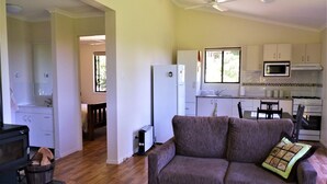 A living room with a sofa, a dining table, and a kitchen area with cabinets and appliances.