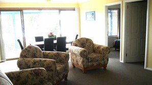 Una sala de estar con sofás de estampado floral, una mesa de comedor con sillas y vistas a través de un ventanal grande.