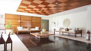 Een moderne woonkamer met een houten plafond, een grote zithoek, een salontafel en twee planten in potten.
