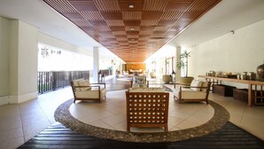 Een ruime lobby met een houten plafond, een centraal zitgedeelte en uitzicht op de omgeving.