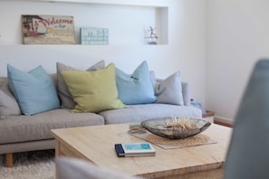 Un salon avec un canapé gris, une table basse en bois et un bol décoratif.