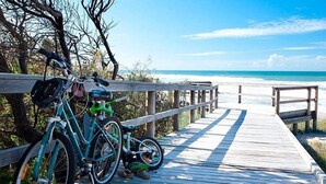 A wooden boardwalk leading to a beach with bicycles parked on it. - Green House Pet-Friendly Beach House (Mount Coolum)