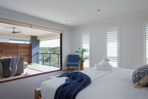 Une chambre avec un lit, une chaise, une plante en pot et un balcon avec vue.