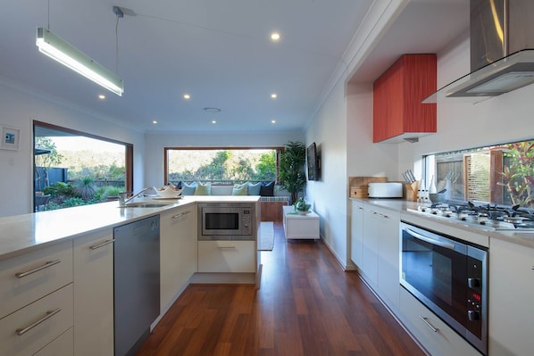 A modern kitchen with a central island, built-in oven, and a stove.