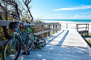 A wooden boardwalk leading to a beach with bicycles parked on it.