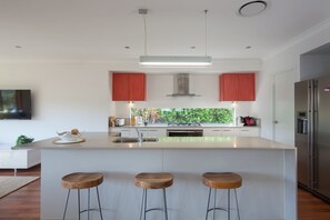 A modern kitchen with a central island, stainless steel appliances, and red cabinetry.