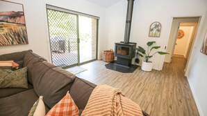 Un salon chaleureux avec un canapé marron, une cheminée et une porte-fenêtre coulissante donnant sur un espace extérieur.