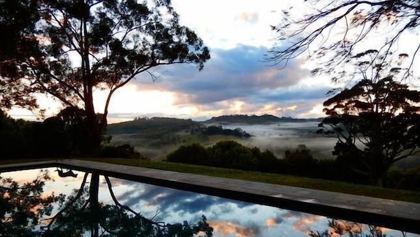 Ein Pool, der Bäume und eine Berglandschaft im Abendlicht spiegelt.