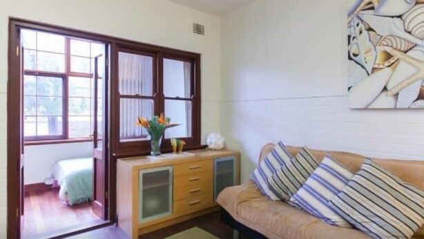 A room with a bed, a wooden cabinet, a sofa, and a painting on the wall.