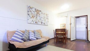 A living room with a sofa, a dining table with chairs, and a door with a frosted glass panel.