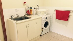 A compact laundry area with a washing machine, a sink, and a drying rack. - Clarevale Cottage B&B (Clare)