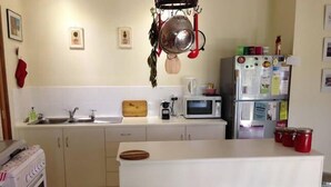 A compact kitchen with a microwave, sink, and two stools. - Clarevale Cottage B&B (Clare)