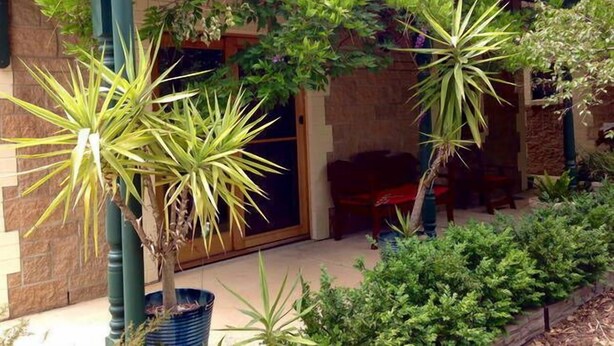 A building with a stone facade, a covered porch with potted plants, and a window with a view of the interior. - Clarevale Cottage B&B (Clare)